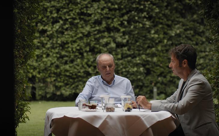 Кадр из фильма «Дарио Ардженто: Паника», два мужчины обедают за столом в саду