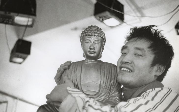 Кадр из фильма «Нам Джун Пайк: Луна — первый телевизор», мужчина со статуей будды