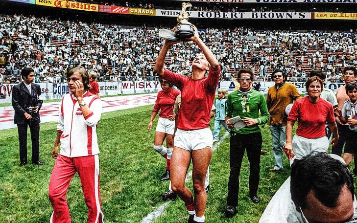 Кадр из фильма «COPA 71», женская футбольная команда идет по полю стадиона с кубком победителей