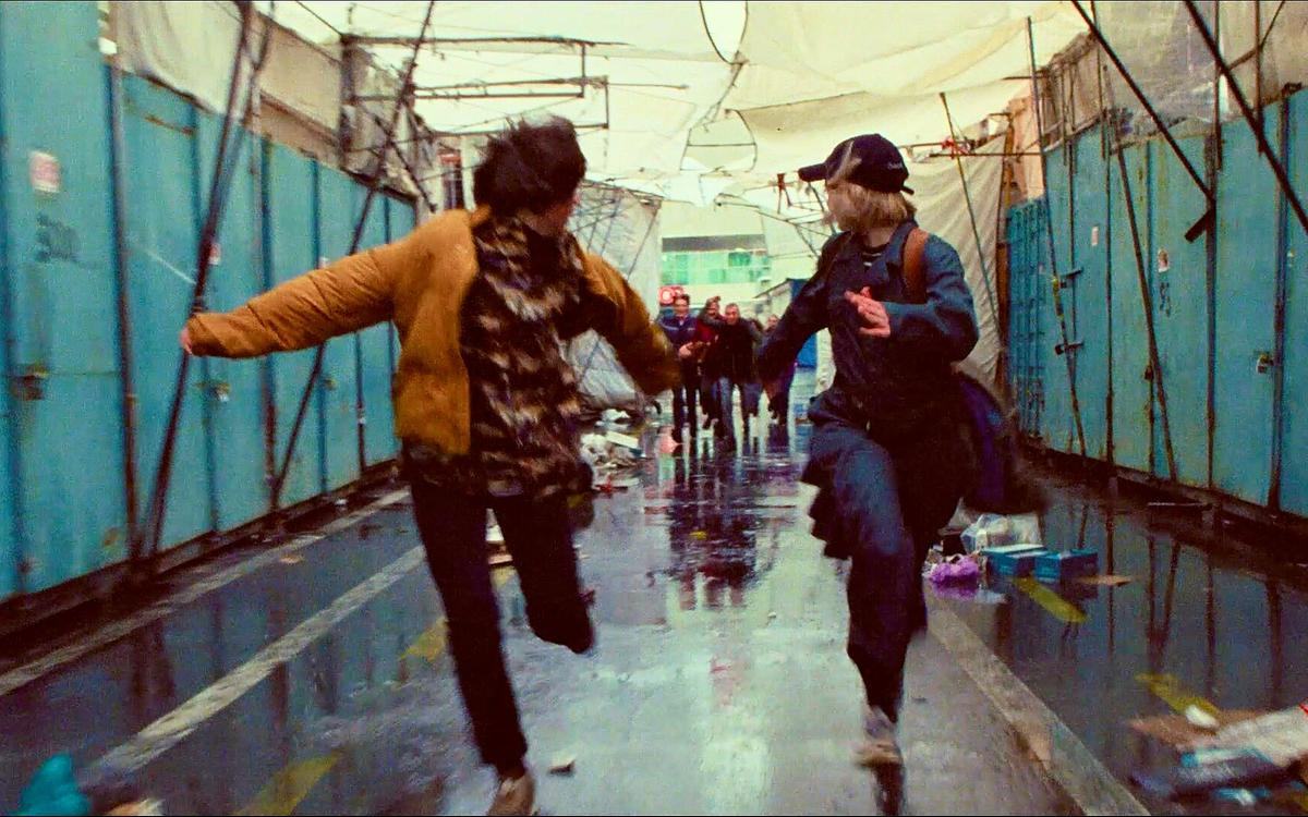 Кадр из фильма «Межсезонье», два подростка убегают от толпы мимо гаражей