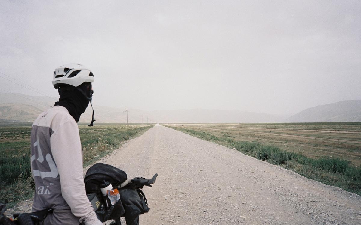 Кадр из фильма «Нешелковый путь», велосипедист смотрит вдаль на обочине грунтовой дороги