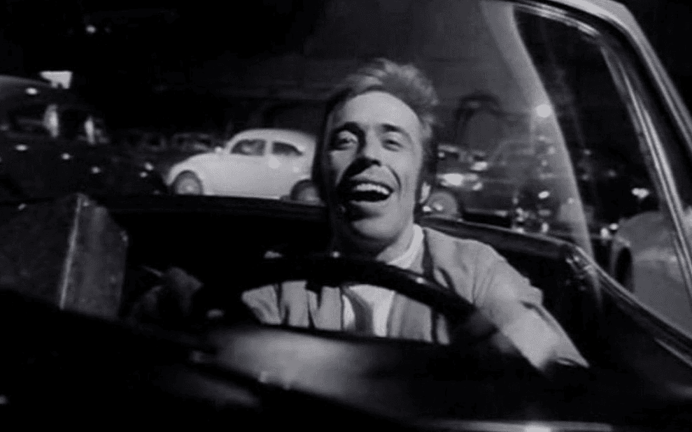 Кадр из фильма «Бандит с красным фонарем», мужчина едет за рулем автомобиля и смеется