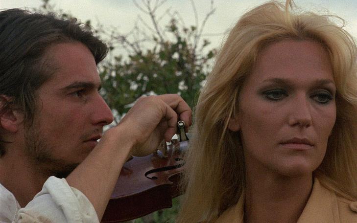 Кадр из фильма «Лев с семью головами», мужчина играет на скрипке возле женщины