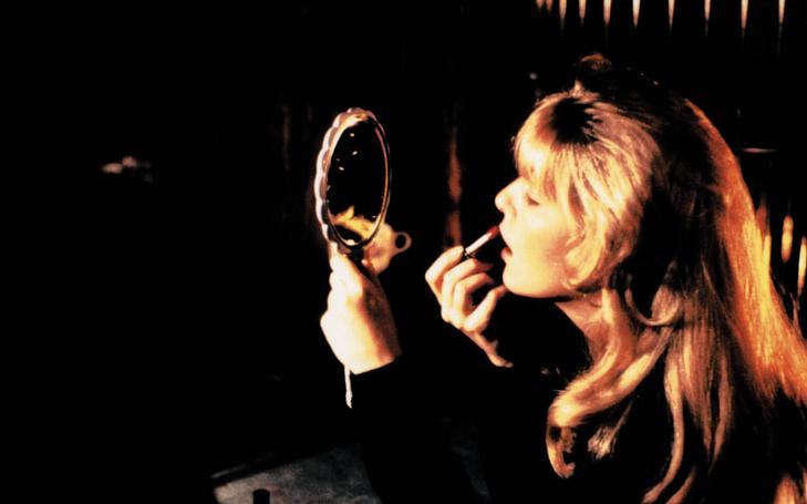 Кадр из фильма «Твин Пикс: Сквозь огонь», женщина смотрит в зеркало ручное и красит губы