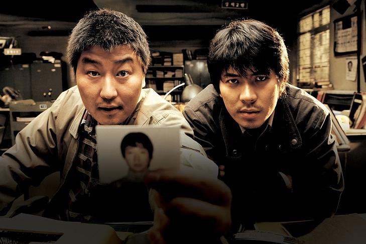 Кадр из фильма «Воспоминания об убийстве»,  два мужчины смотрят в камеру и показывают фото человека