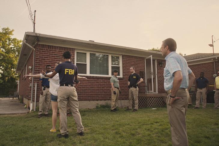 Кадр из фильма «Реальная история Уиннер», агенты ФБР обыскивают людей на фоне дома