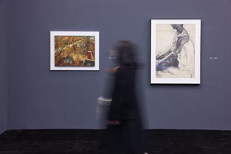 Две картины на фиолетовой стене и проходящий мимо них посетитель в расфокусе