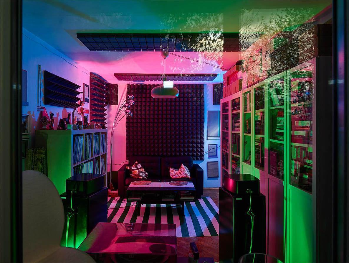 Титульное изображение для страницы события: фотография интерьера квартиры, диван под окном, окно завешано звукоизоляционным материалом, освещение зелено-розовым светом