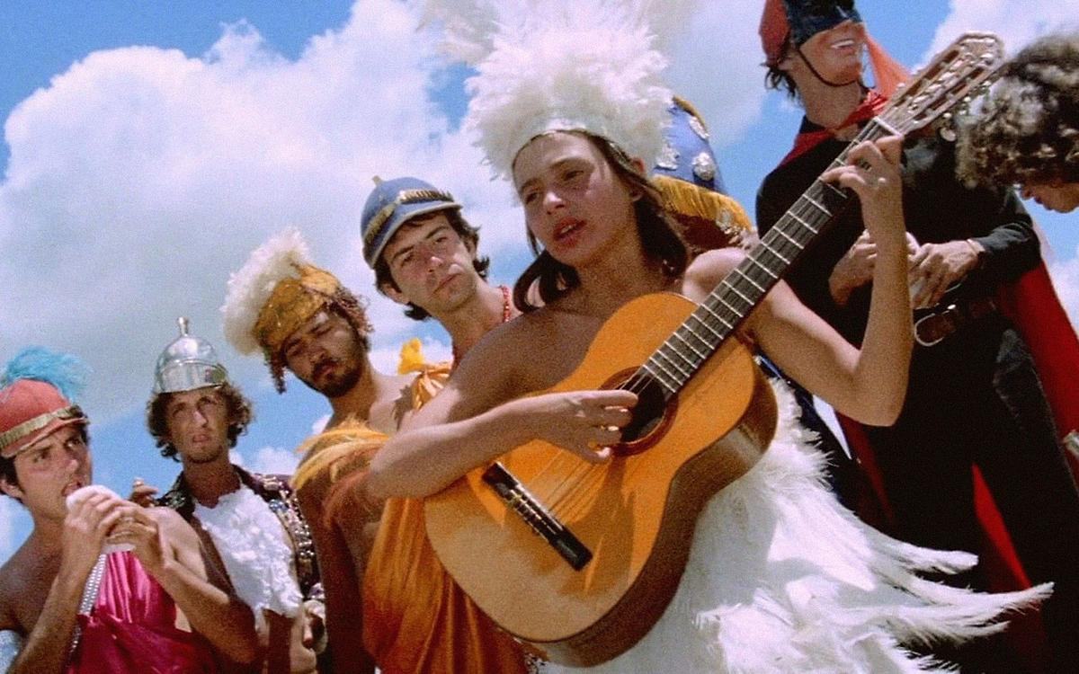 Кадр из фильма «Возраст Земли», люди в карнавальных костюмах играют на гитаре