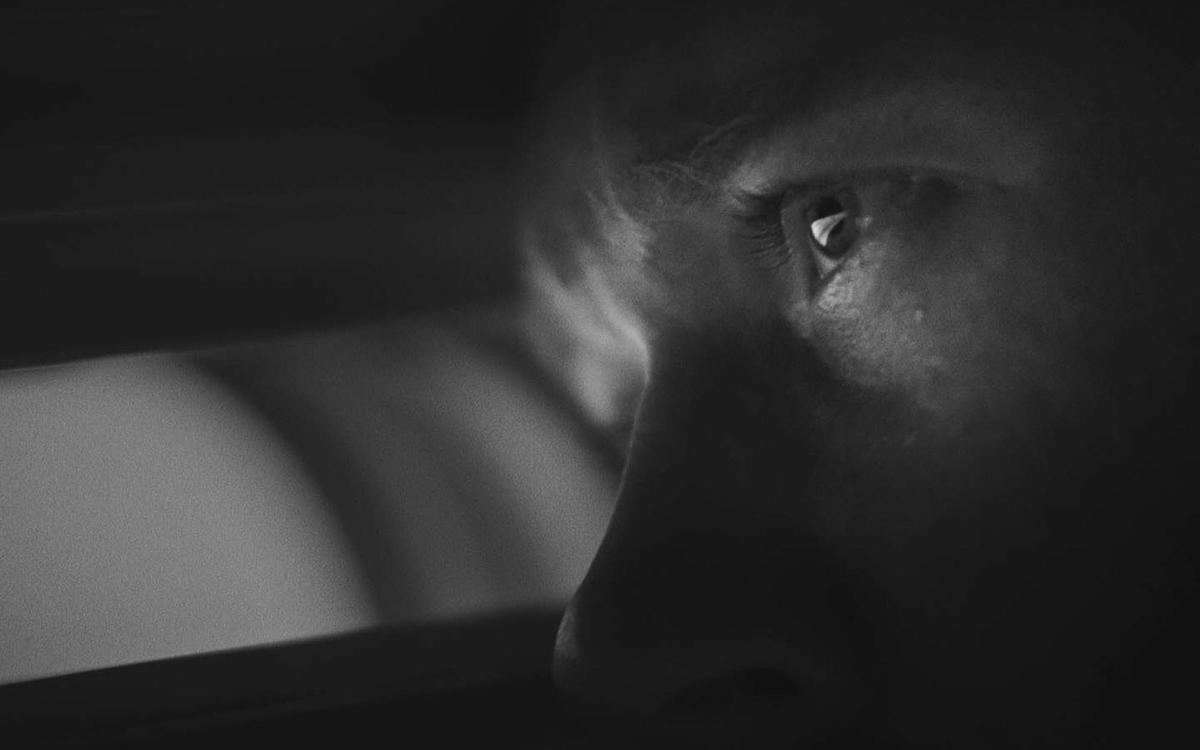 Титульное изображение для страницы события: кадр из фильма «Волнами», черно-белое изображение, мужской глаз смотрит в щелку крупным планом