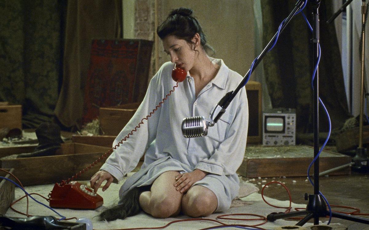 Титульное изображение для страницы события: кадр из фильма «Пиаффе», девушка сидит на полу перед микрофоном и звонит по красному телефону с вертушкой