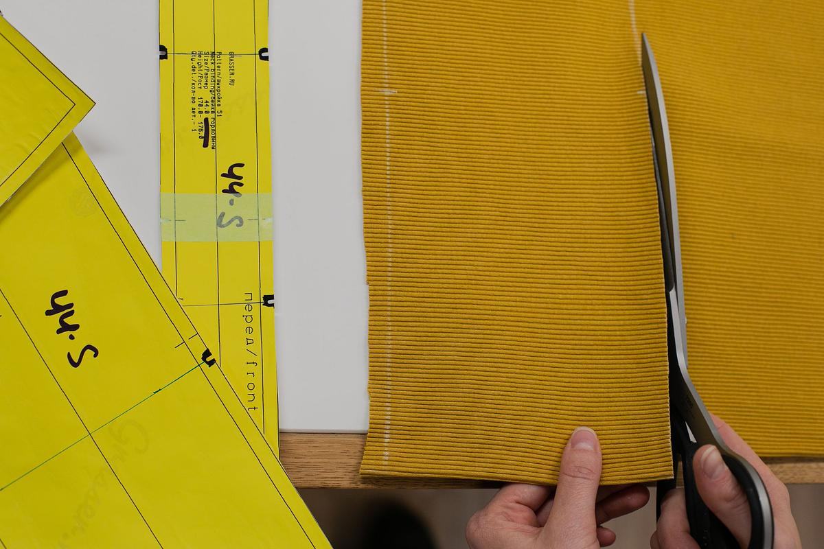 Титульное изображение для страницы события: крупным планом кусок ткани горчичного цвета и руки человека — в правой ножницы, которыми он начал разрезать ткань, а левая рука придерживает кусок ткани за край