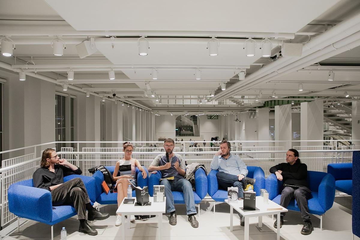 Титульное изображение для страницы события: участники дискуссии сидят в синих креслах в библиотеке ГЭС-2