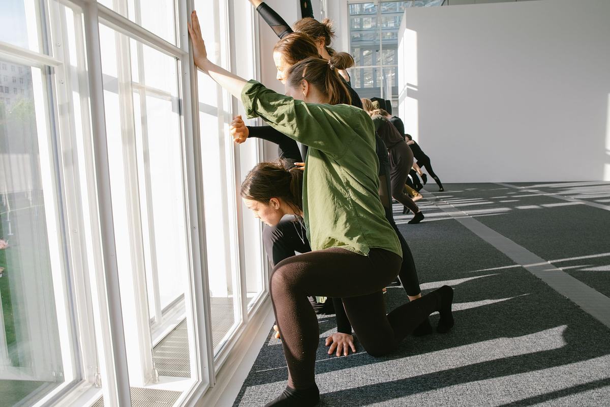 Титульное изображение для страницы события: люди стоят в ряд перед большими окнами и опираются на них обеими руками