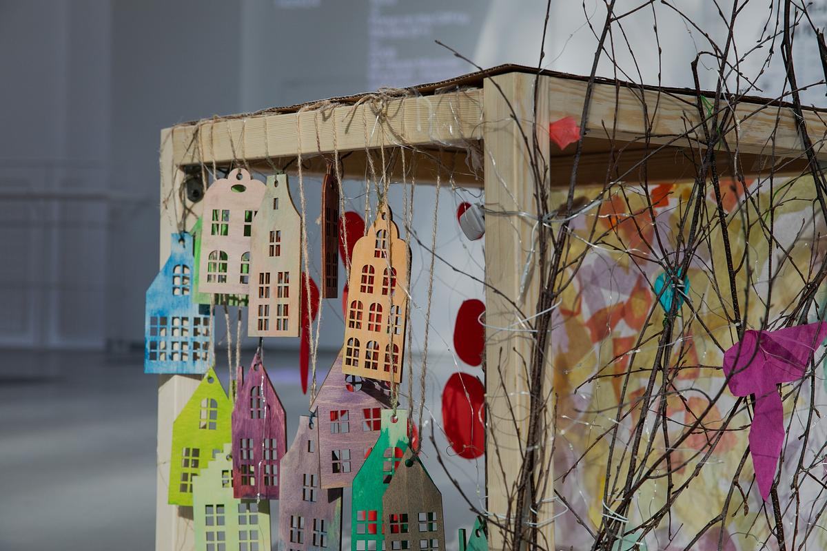 Бумажные домики на веревочках подвешены на грань разноцветного куба