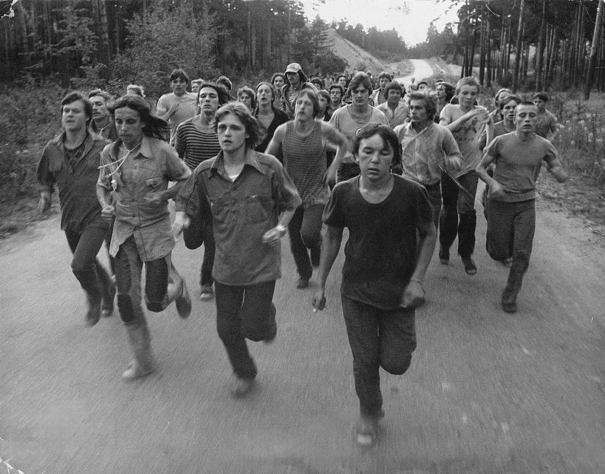 Черно-белый кадр из фильма Дианы Асановой «Пацаны». Группа молодых людей бежит по дороге