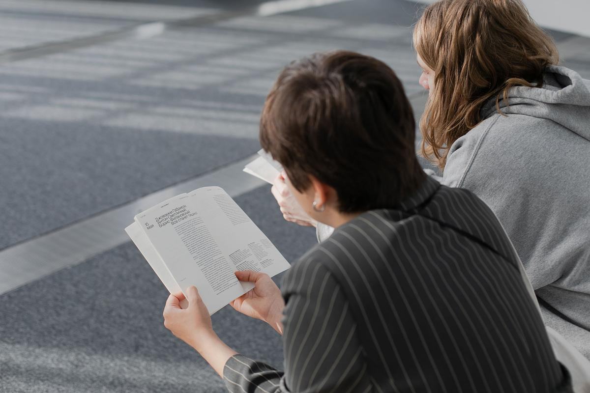 Два человека сидят спиной к зрителю и читают книги