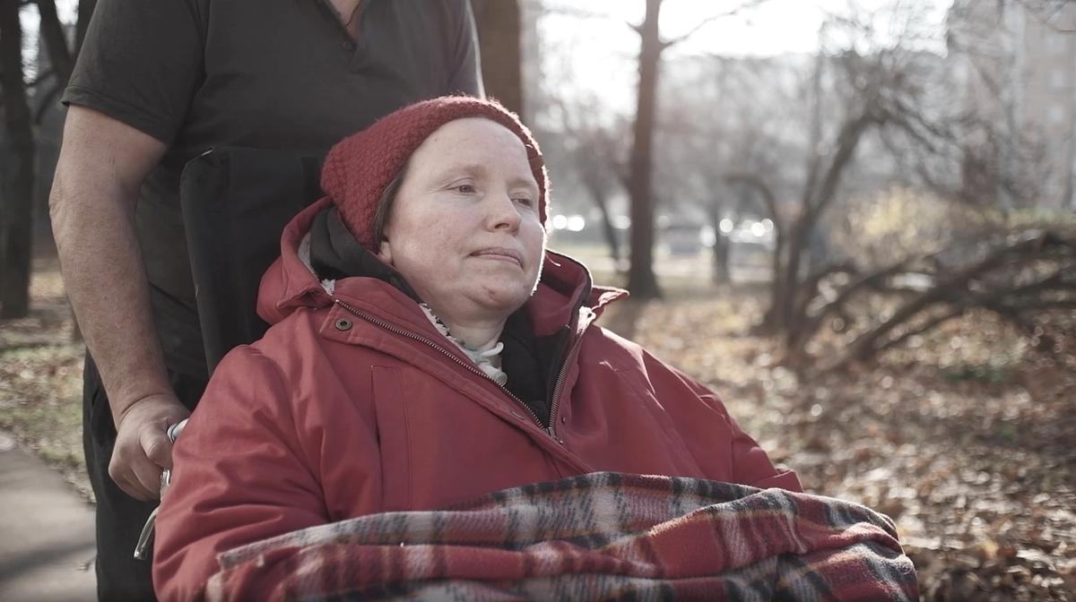Кадр из фильма «Дышать», женщину на инвалидной коляске везет мужчина по осеннему парку