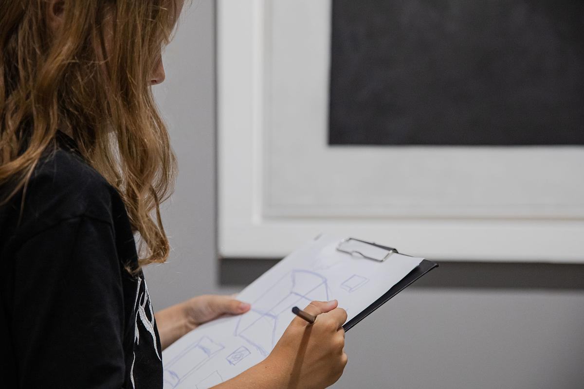 Девушка рисует держит в руках планшет и рисует куб