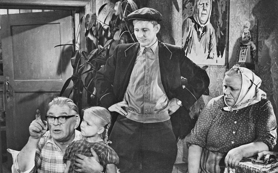 Кадр из фильма «Полустанок», мужчина в кепке стоит в окружении семьи