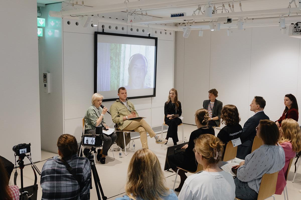 4 спикера сидят с микрофонами перед аудиторией