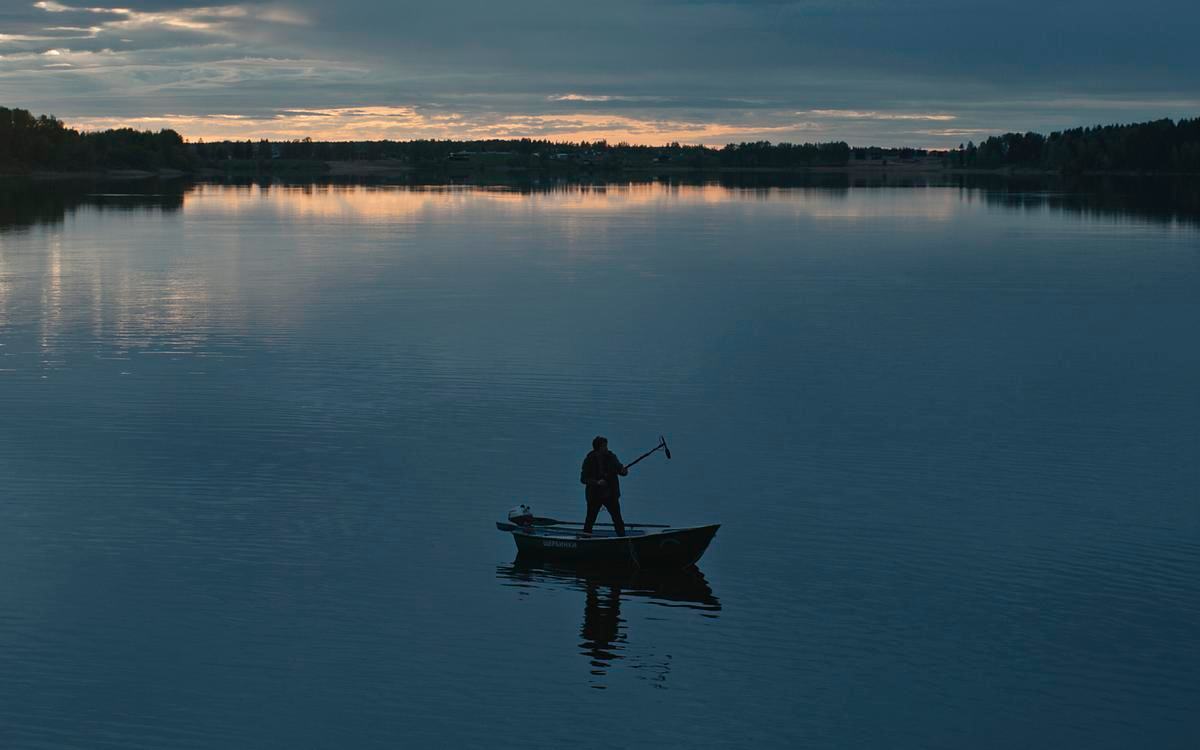 Кадр из фильма «Пепел и доломит», мужчина стоит в лодке с шестом в руке посреди озера