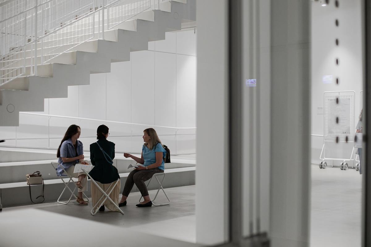 Люди сидят на стульях в ГЭС-2 и общаются