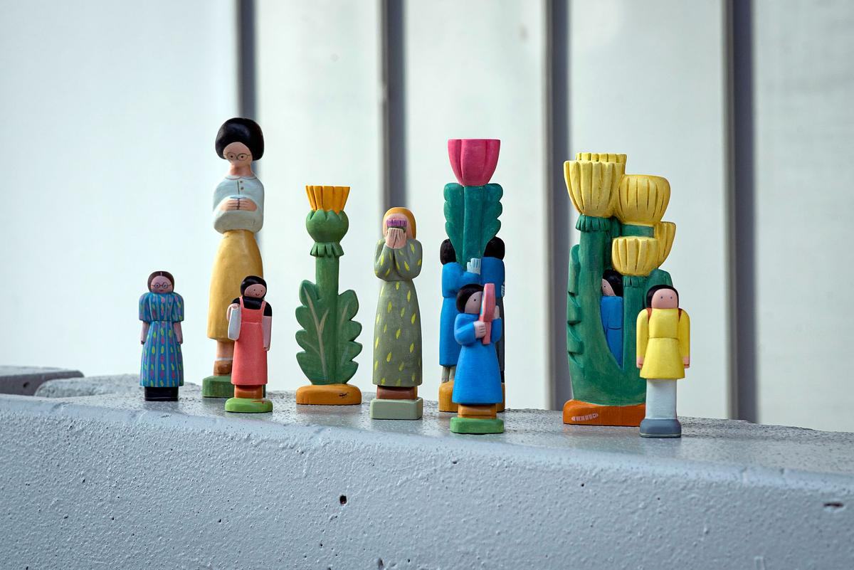 Фото, стоят в ряд глиняные человечки и цветочки