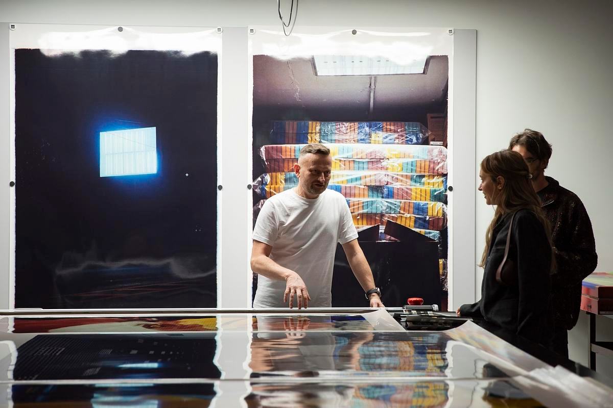 Фото, трое человек разговаривают возле картин