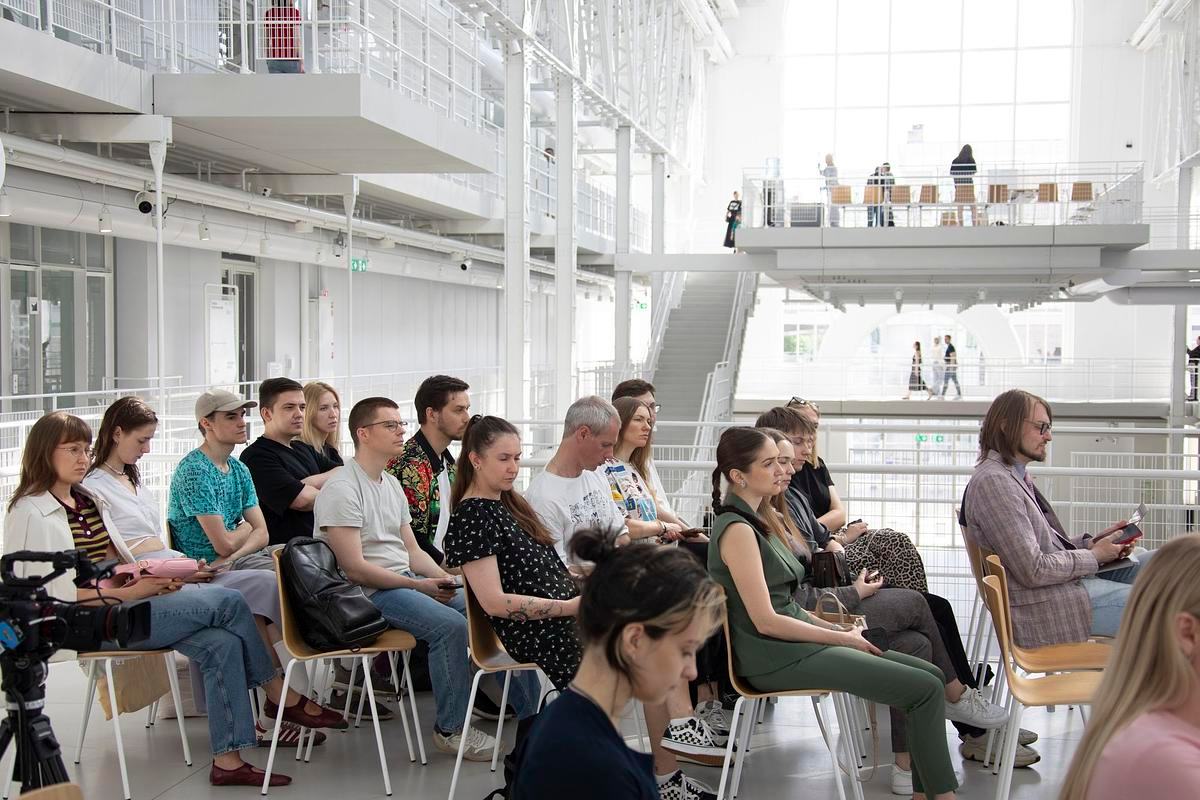 Фото, вид сбоку, люди сидят на лекции на фоне правой платформы