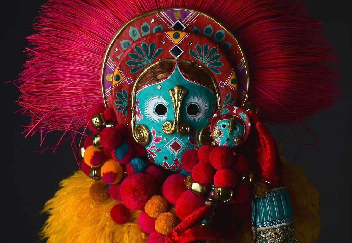 Фото, колумбийская маска бирюзовая с красными и розовыми рисунками, шариками и перьями