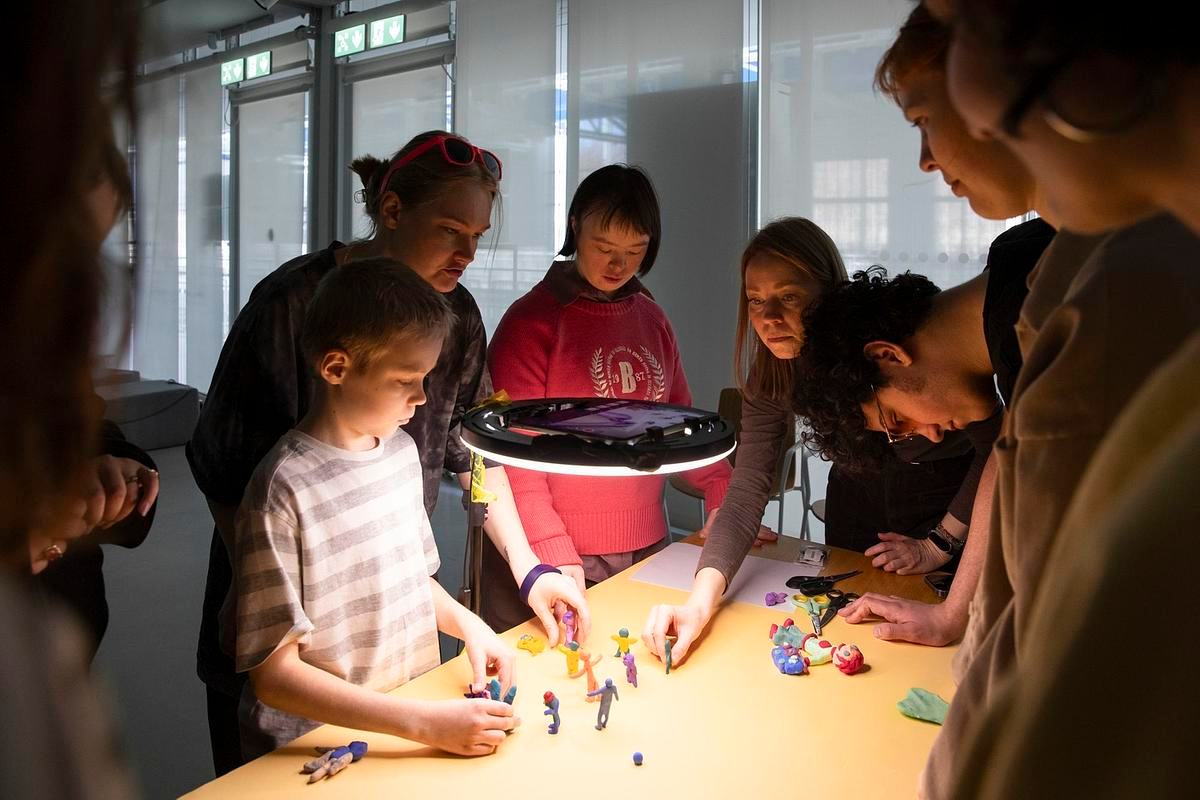 Фото: дети с родителями собрались у лампы с пластилиновыми человечками