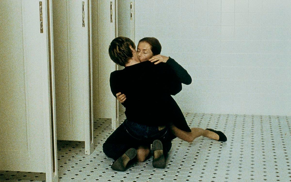 Кадр из фильма «Пианистка», 2 человека целуются, сидя на коленях на полу общественного туалена