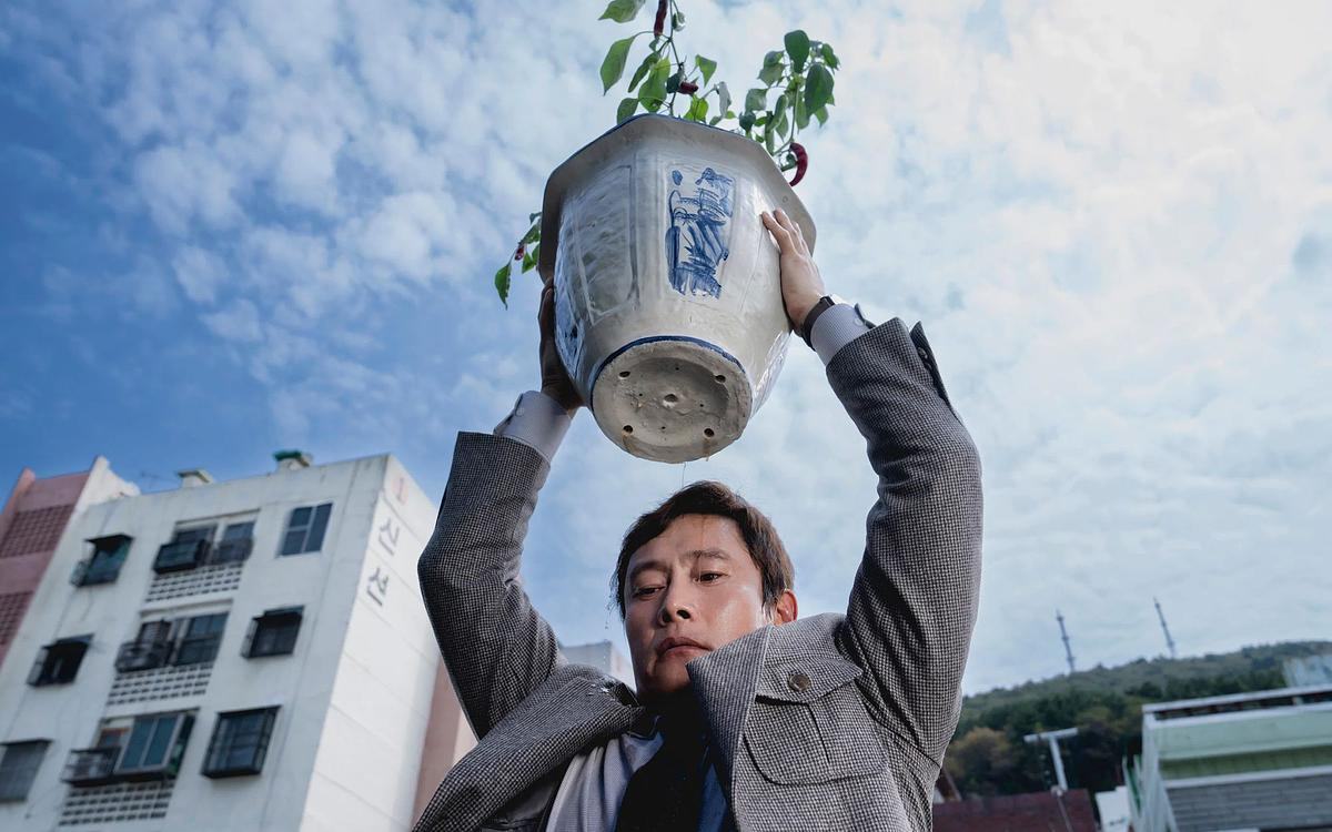 Кадр из фильма «Метод исключения», мужчина поднял над головой горшок с цветком