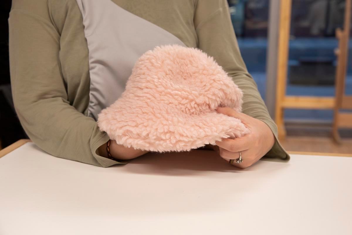 Руки держат розовую меховую панаму