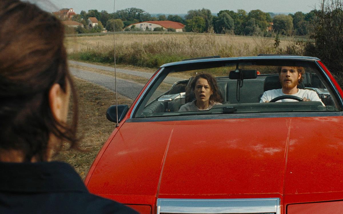 Кадр из фильма «Отражения № 3», люди в красной машине смотрят на женщину