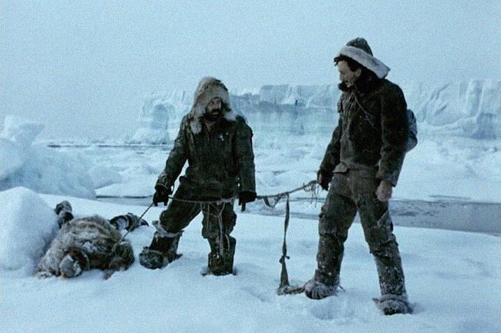 Кадр из фильма «Красная палатка», 2 мужчин стоят во льдах возле одного лежащего человека