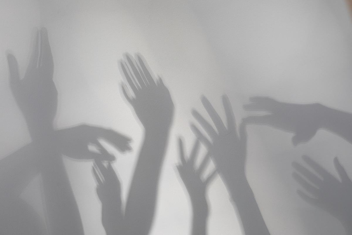 Тени вытянутых рук на белой стене