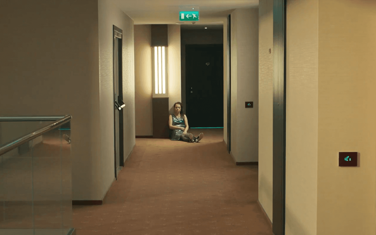 Кадр из фильма "Паркет", девушка сидит на полу в коридоре