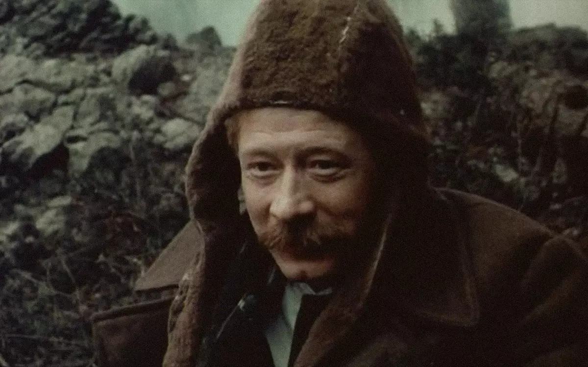 Кадр из фильма «Повесть непогашенной луны», мужчина в куртке с капюшоном на фоне скалы