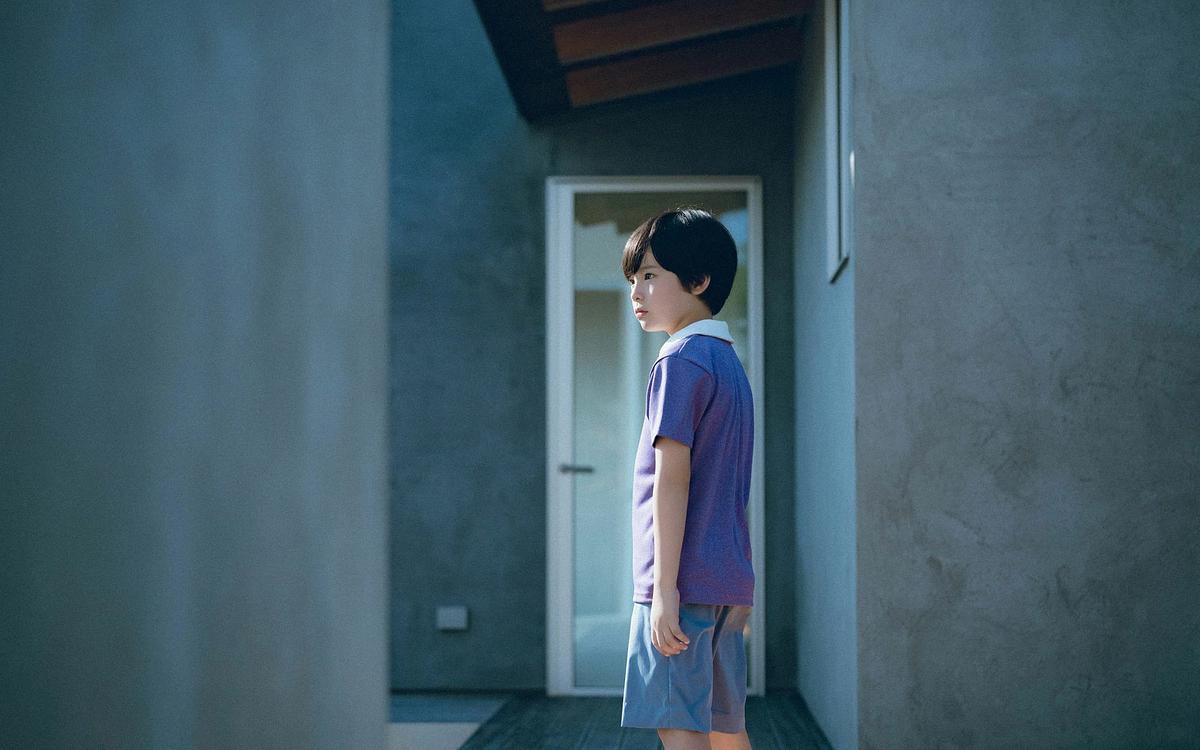 Кадр из фильма «Барашек в ящике», мальчик стоит на фоне серого дома