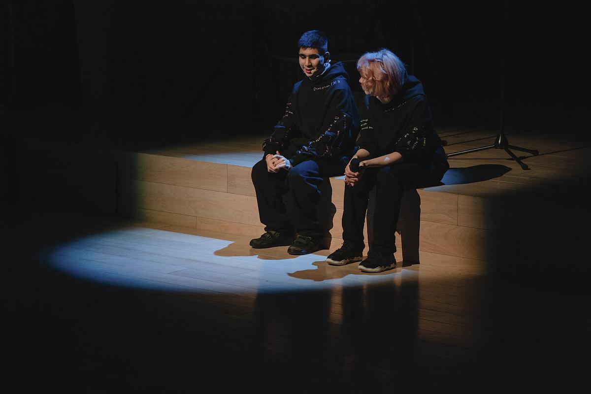 Титульное изображение для страницы события: театральная сцена, темно, в круге света на ступеньке сидят и разговаривают молодой человек и женщина
