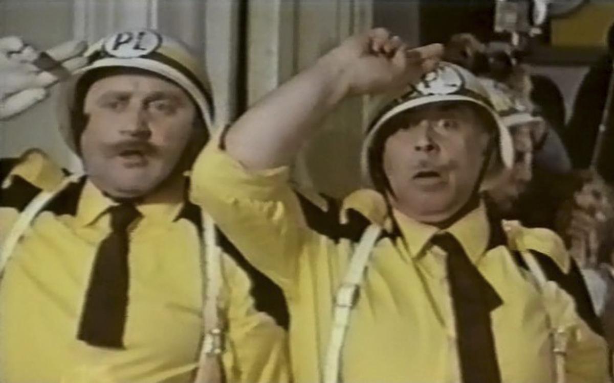 Титульное изображение для страницы события: кадр из фильма «Райские яблочки», два мужчины в желтых рубашках, черных галстуках и касках отдают честь