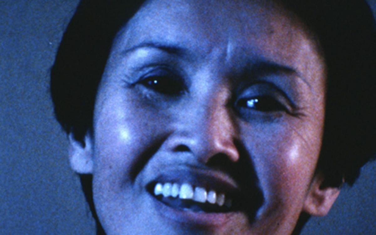 Титульное изображение для страницы события: кадр из фильма «Фамилия Вьет, имя Нам», крупный план улыбающейся азиатской женщины