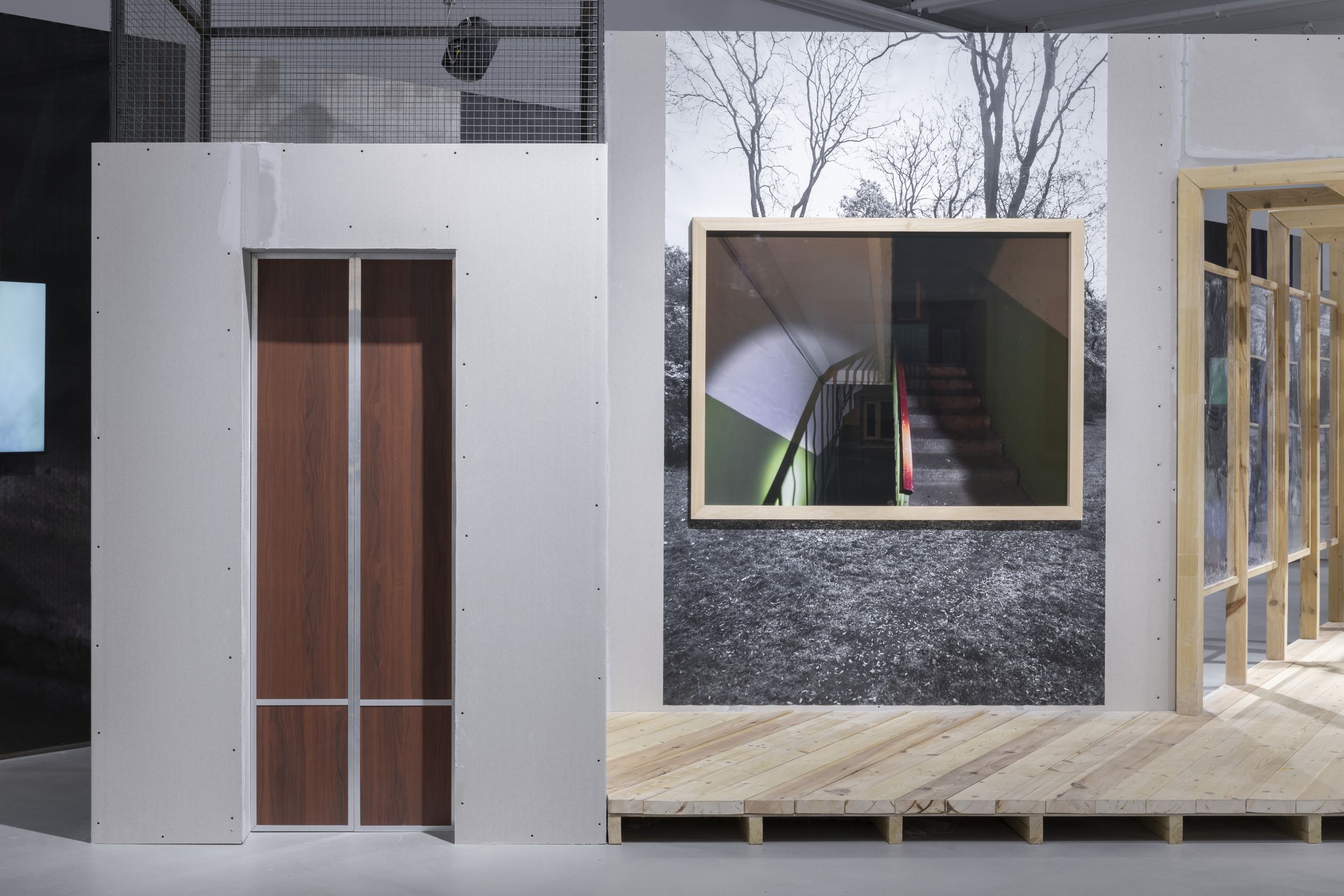 Фотография фрагмента выставки «Дом и сад», декорации: дверь лифта,  оконная рама с фотографией лестничной клетки и деревянный коридор